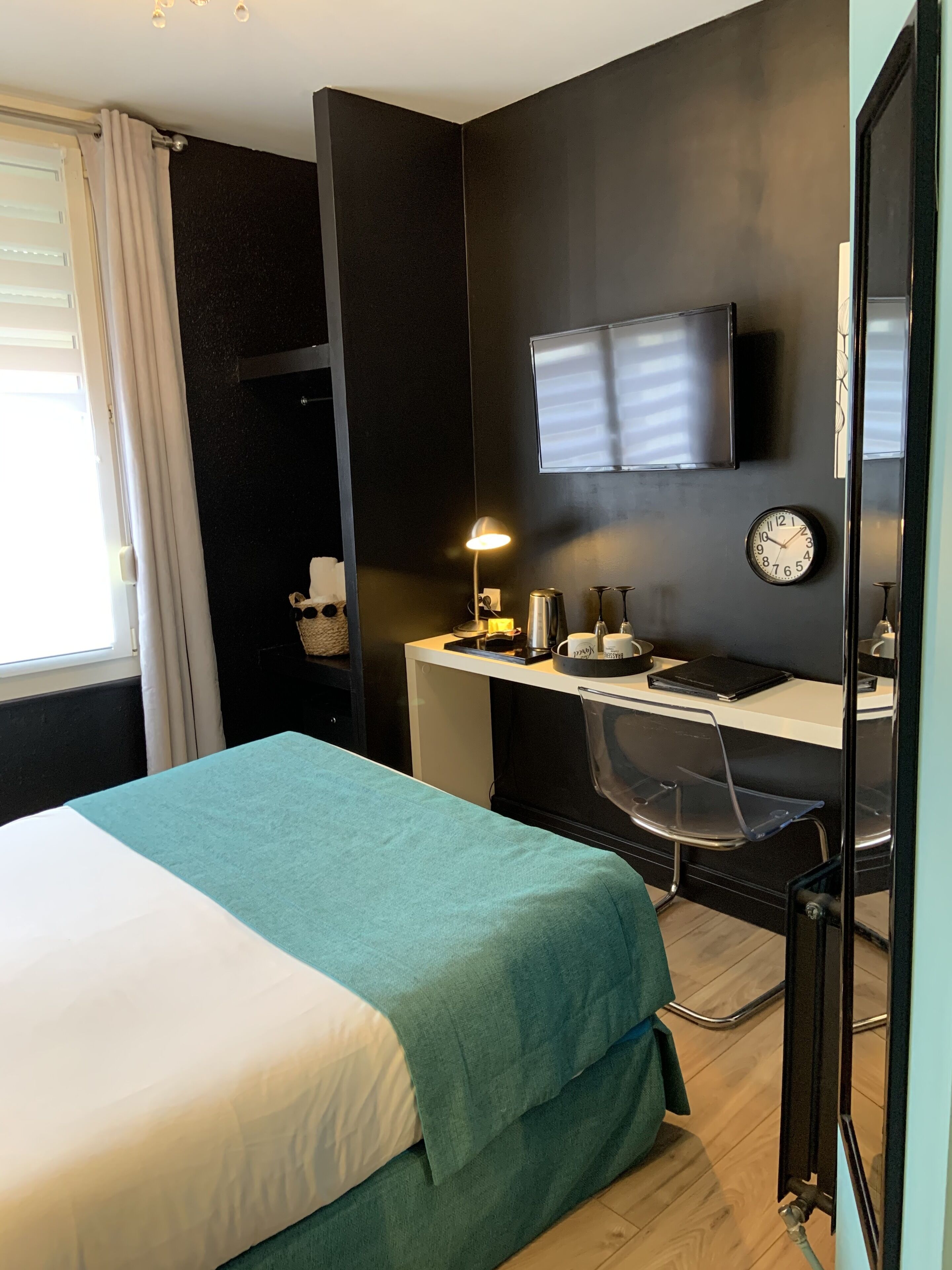 Una habitación de hotel moderna con cama, escritorio, silla y televisor montado en la pared.