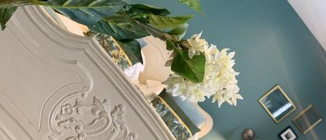 Una habitación con una mesa consola blanca y ornamentada, una pared color verde azulado y un espejo.