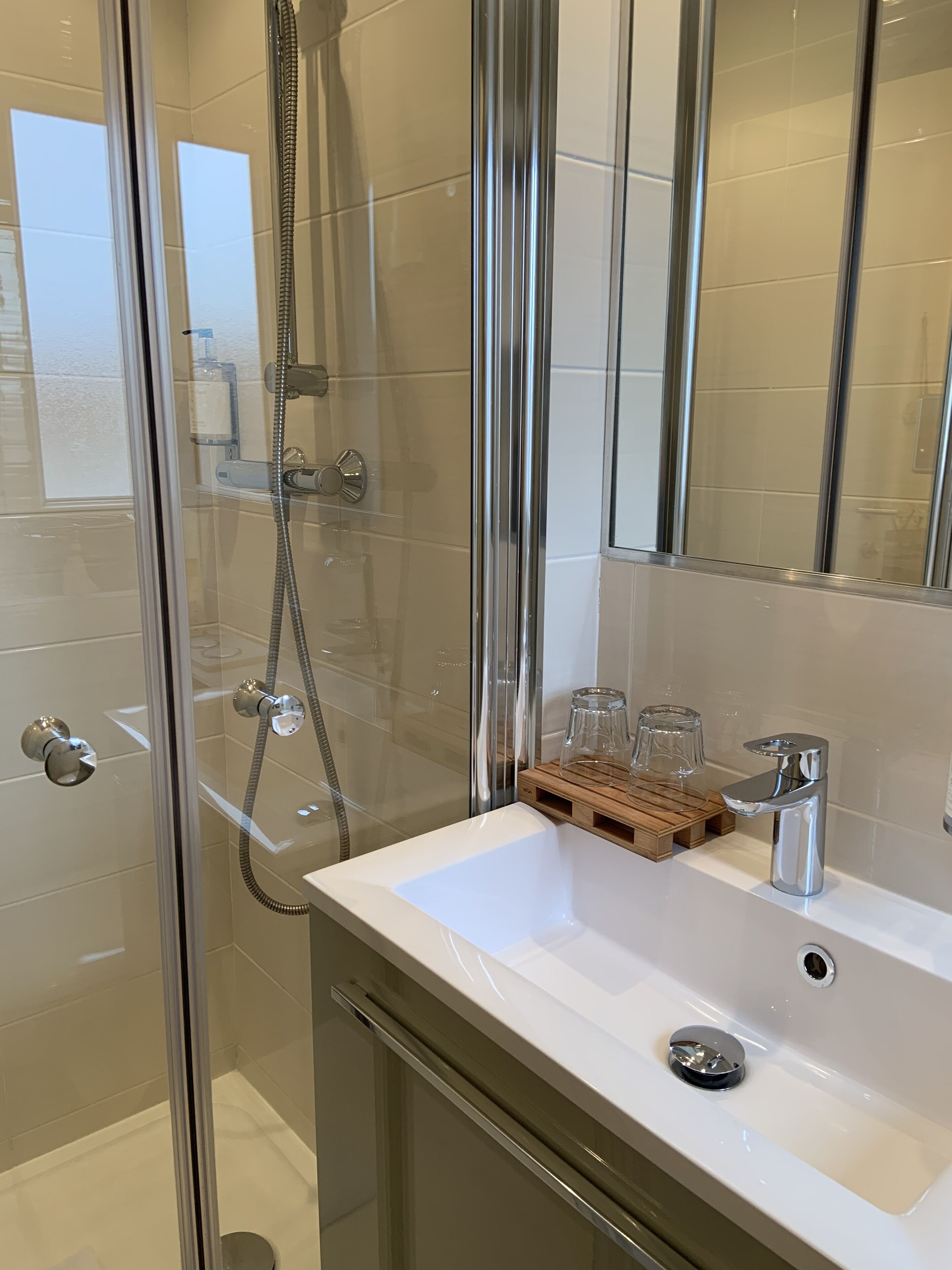 Une salle de bain moderne avec une douche à parois de verre, un lavabo blanc et un miroir au-dessus.