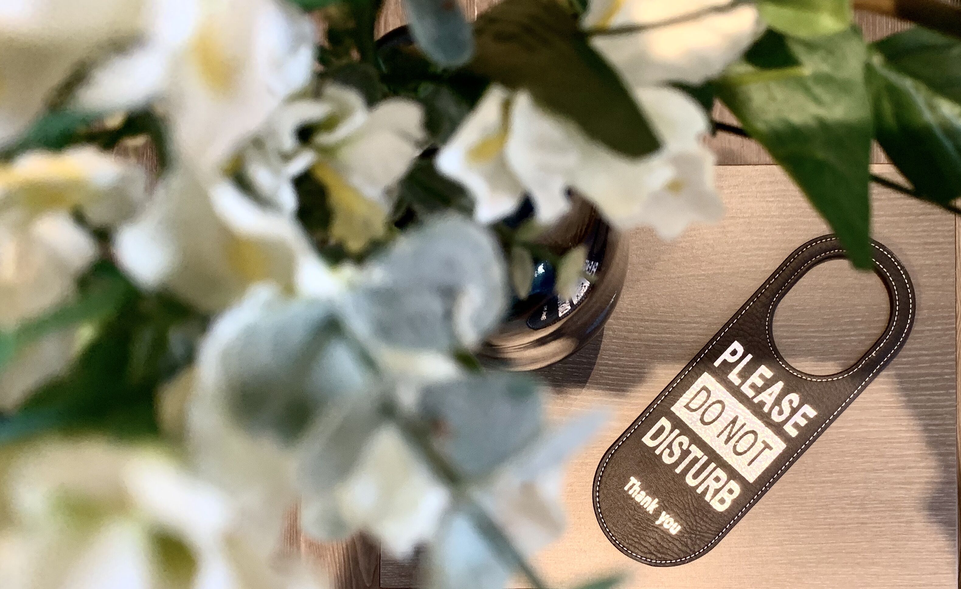 A close-up of a wooden surface with a metal object and a leather tag with text.