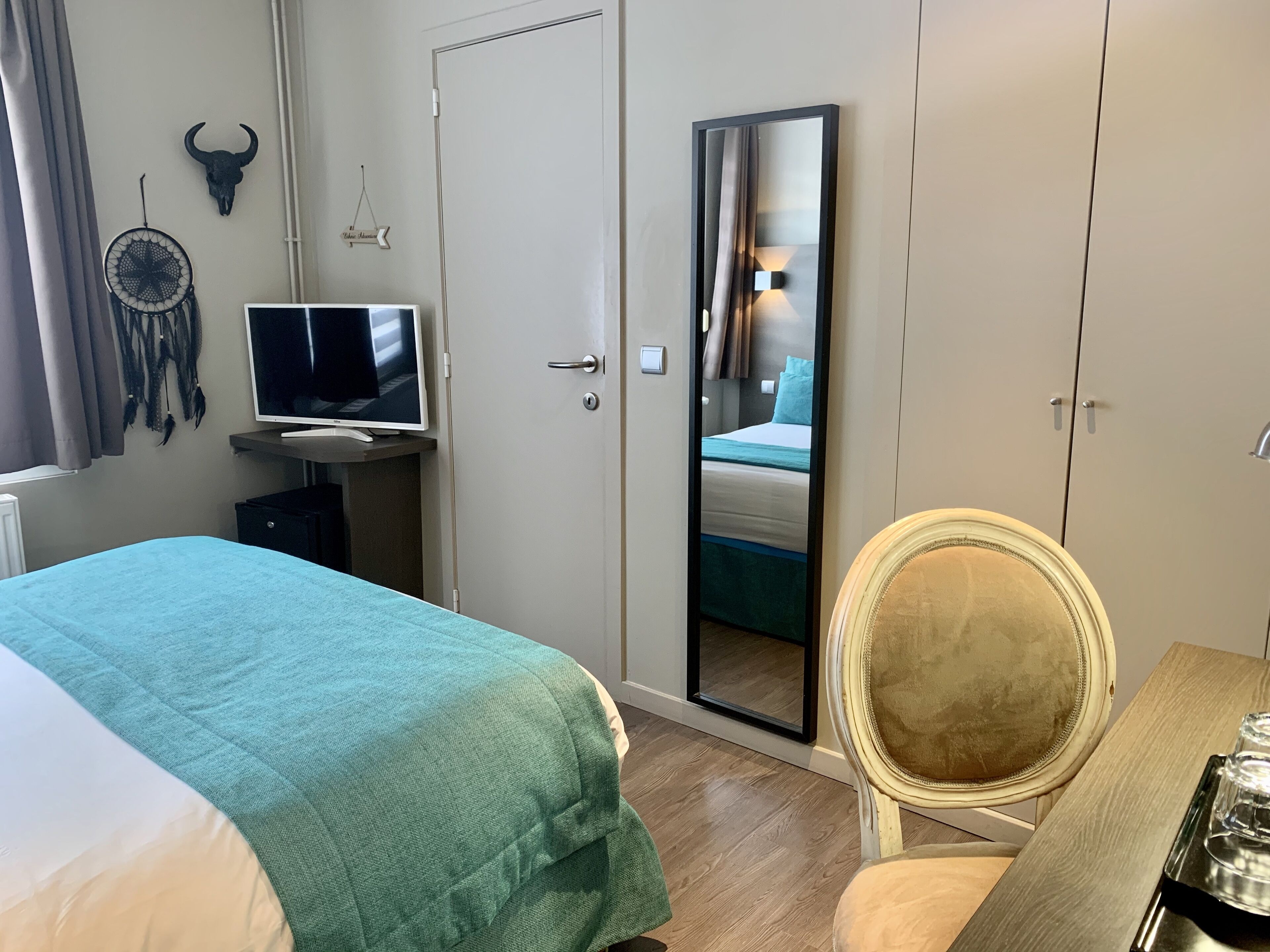 Une chambre d’hôtel équipée d’un lit, d’un bureau, d’une chaise, d’une télévision, d’une armoire et d’un miroir.