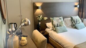 Une chambre d’hôtel avec un lit, une table de chevet, une lampe et un tableau encadré au mur.