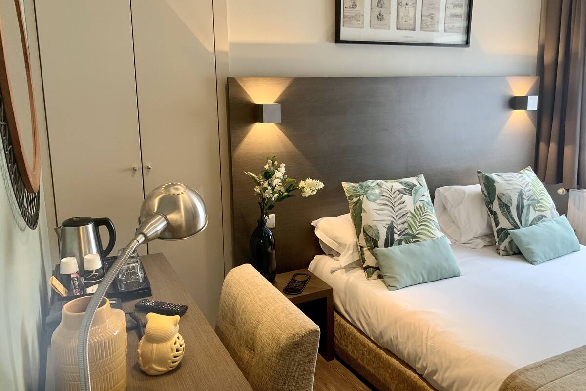 Ein Hotelzimmer mit Bett, Nachttisch, Lampe und einem gerahmten Bild an der Wand.