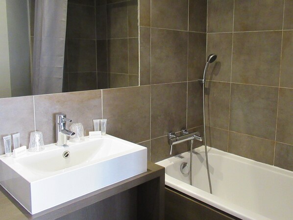 Une salle de bain avec un lavabo blanc, un miroir et une baignoire.