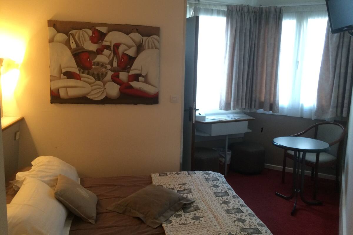 Une chambre d’hôtel avec un lit, un bureau, une chaise et un tableau au mur.