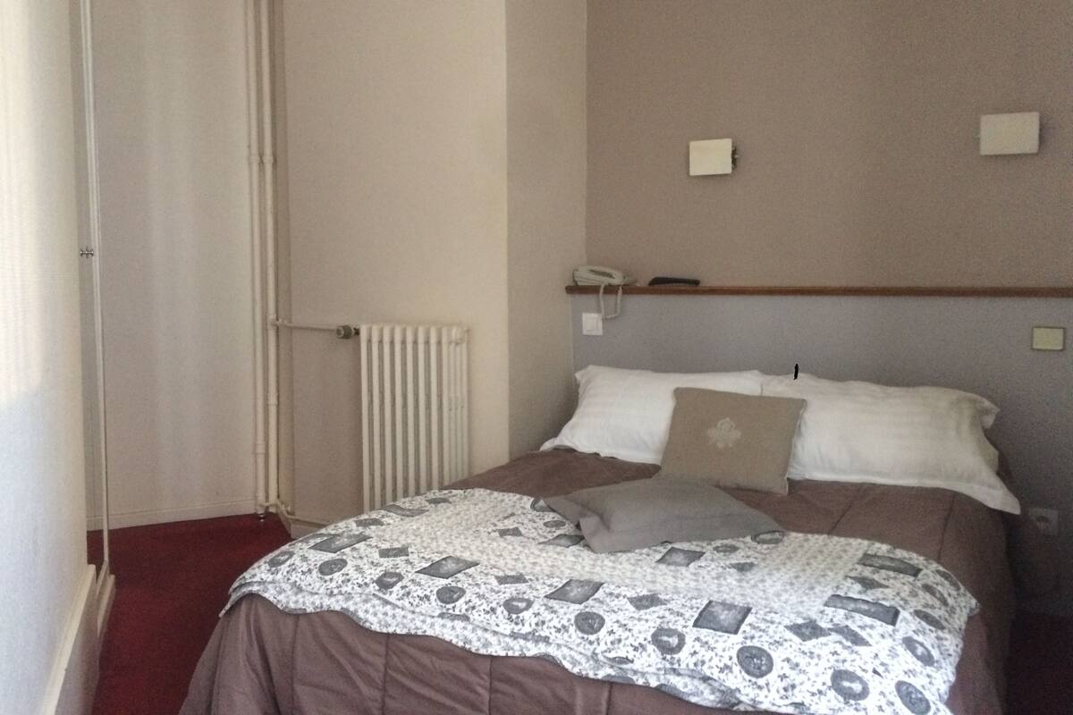 Une chambre à coucher avec un lit, un radiateur, un téléphone et une porte.