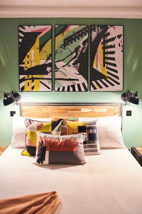 A bed with a wooden headboard, multiple pillows, and a blanket. - Madrigal hotel (Paris)
