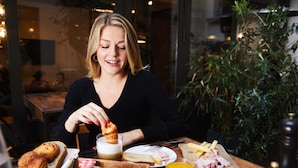 A person sitting at a wooden table with breakfast items including toast, fruit, and a glass of orange juice. - Madrigal hotel (Paris)