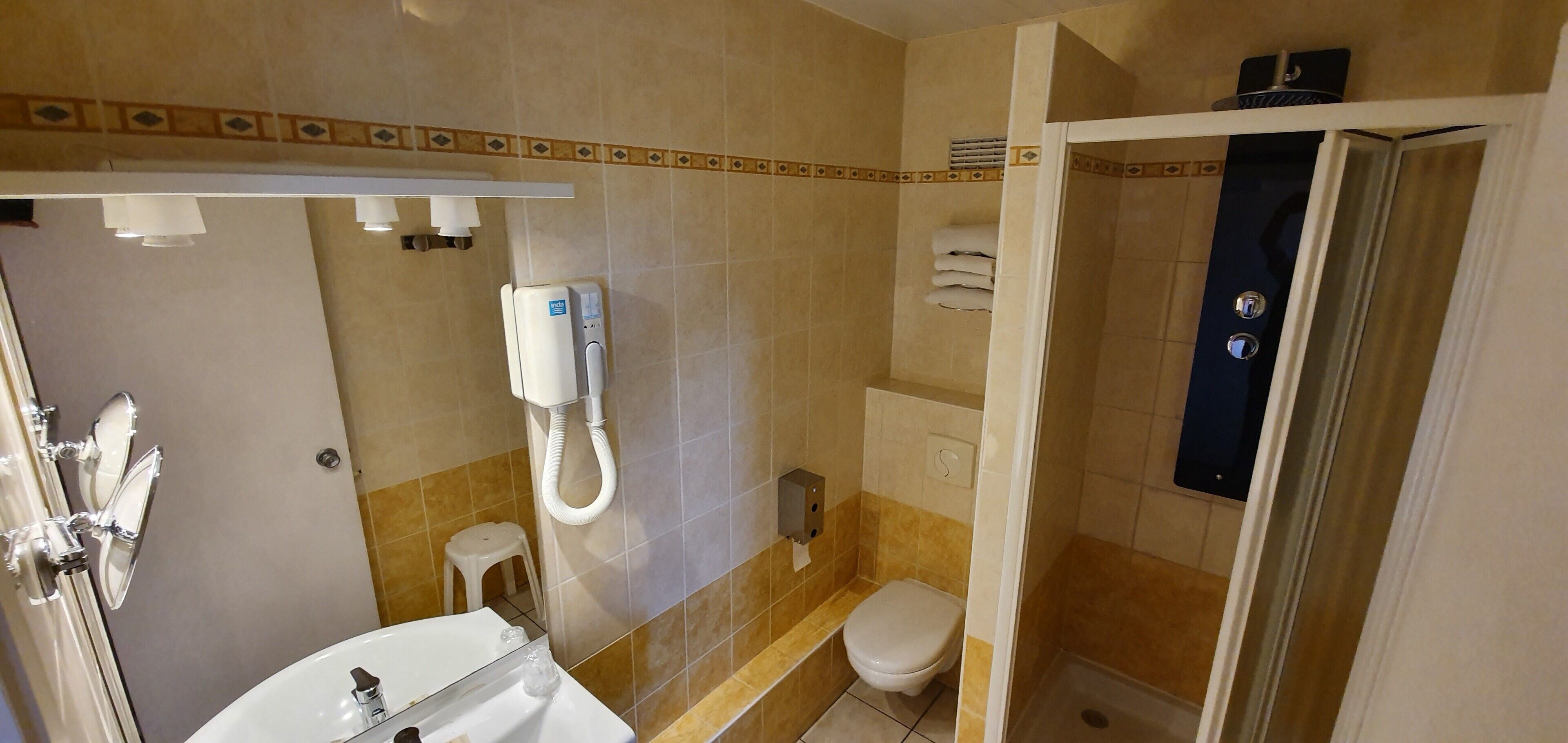 A bathroom with a toilet, sink, and shower area.
