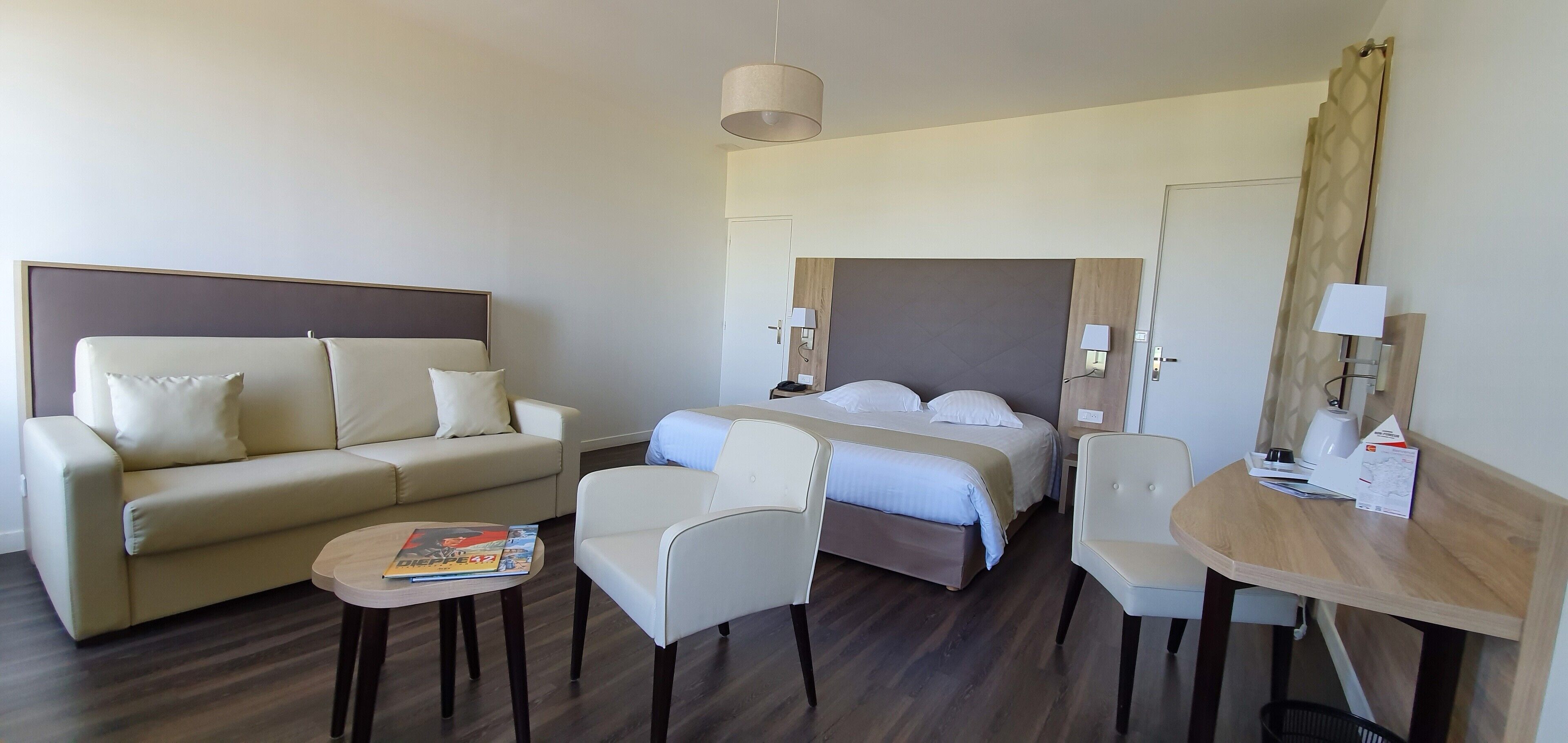 A hotel room with a bed, a sofa, a small table, and a chair.