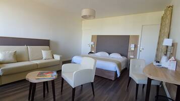 Una habitación de hotel con cama, sofá, una mesita y una silla.