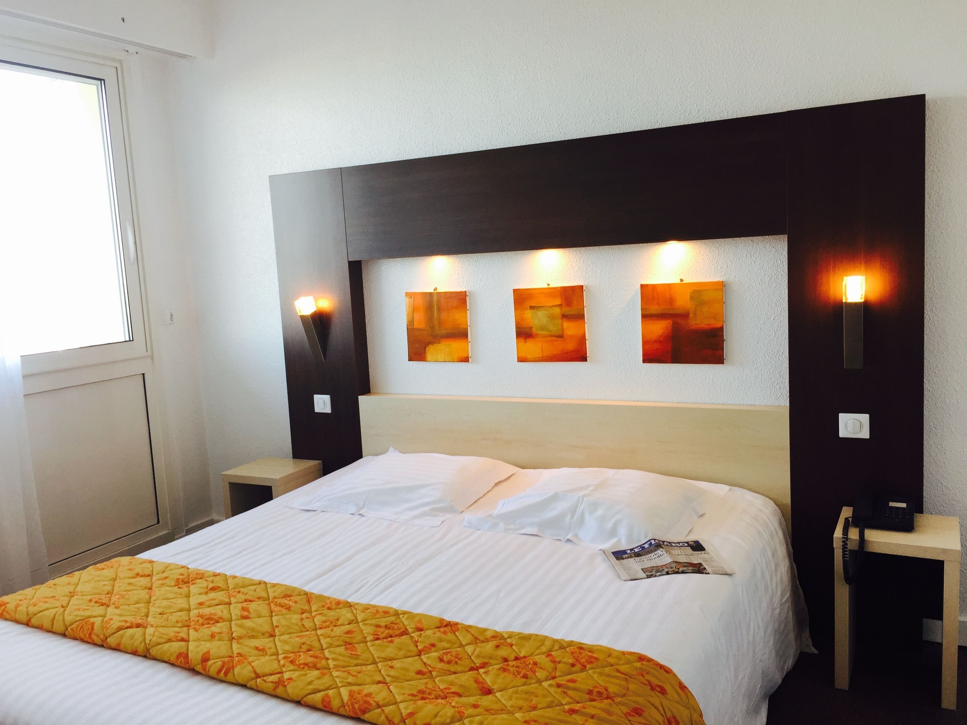 Ein Hotelzimmer mit einem Bett, einem Nachttisch und einer Wandleuchte.