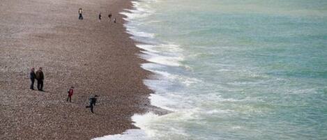 A beach with people walking along the shore.