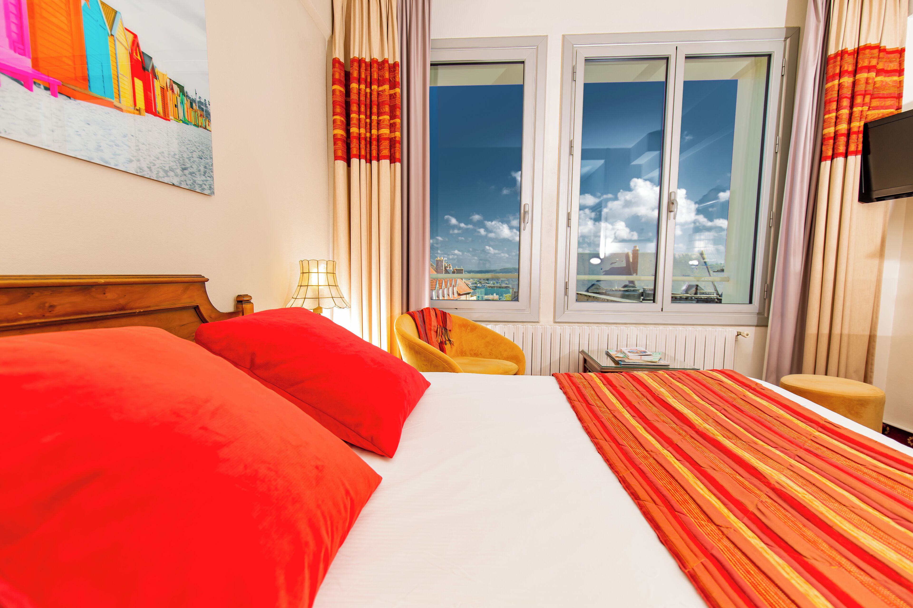 Une chambre d’hôtel avec un grand lit, une chaise, une télévision et une fenêtre donnant sur un beau paysage.