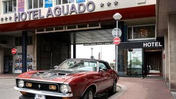 A red vintage car parked in front of Hotel Aguado.