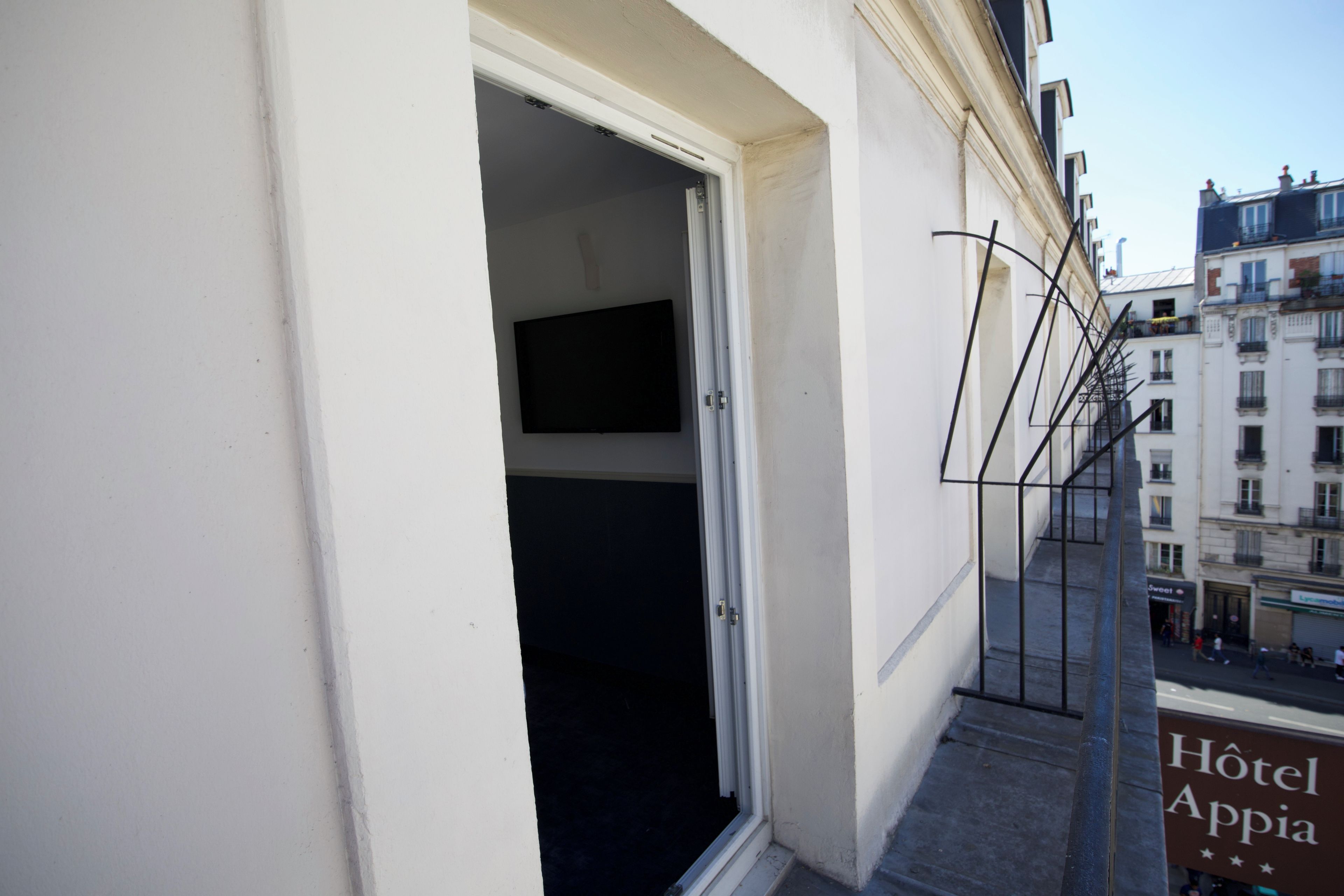 L’entrée d’un hôtel, avec une enseigne indiquant « Hôtel Appia » et un escalier menant à l’entrée.