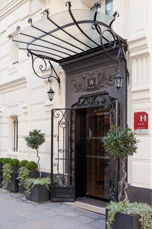En hotelindgang med en jerngitterport, en glasdør og et markise over indgangen.