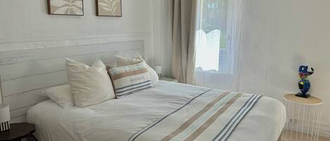 A neatly made bed with a striped blanket, a bedside table with a lamp, and two wall-mounted art pieces.