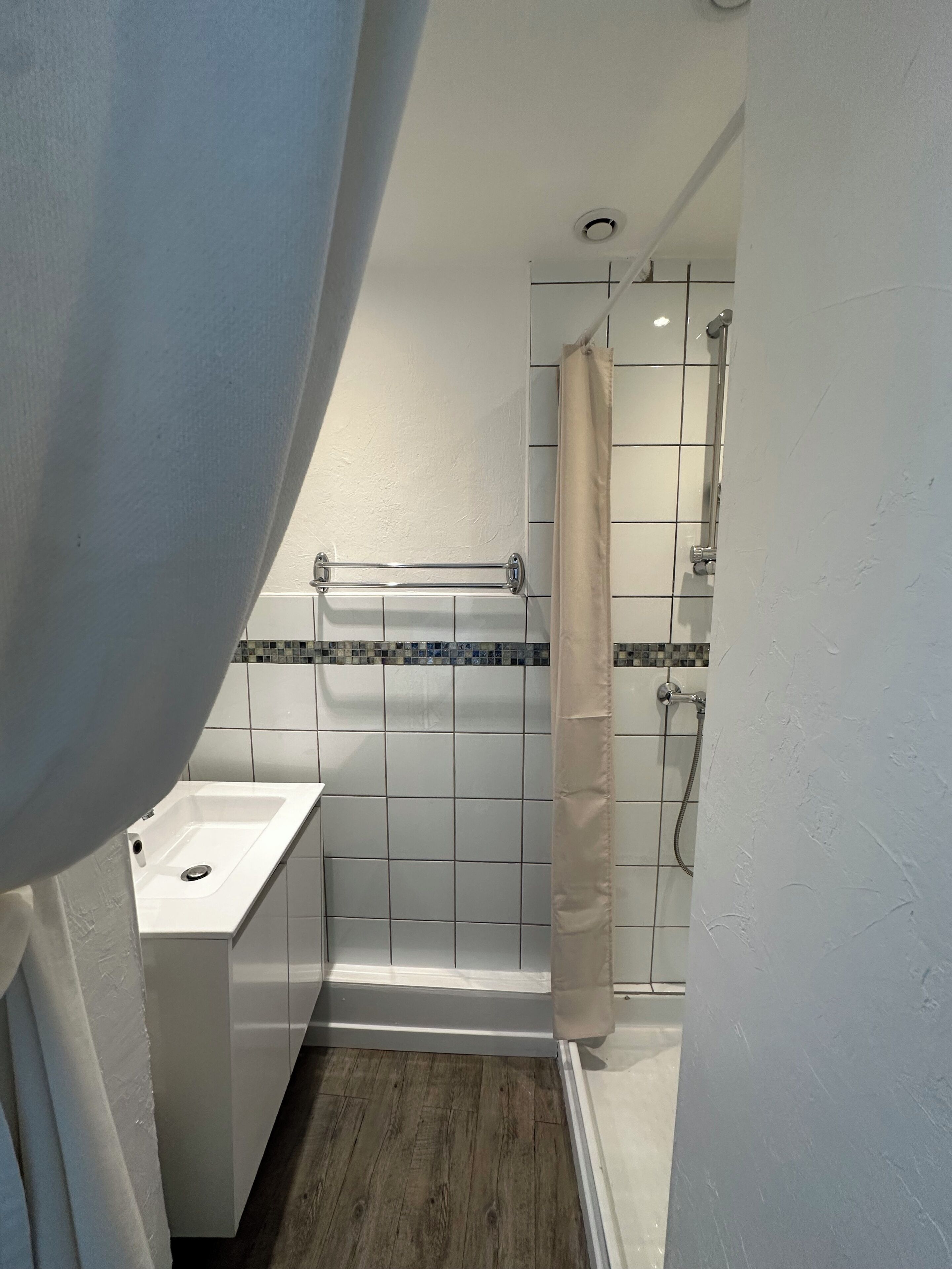 Ein Badezimmer mit Waschbecken, Dusche und gefliesten Wänden.