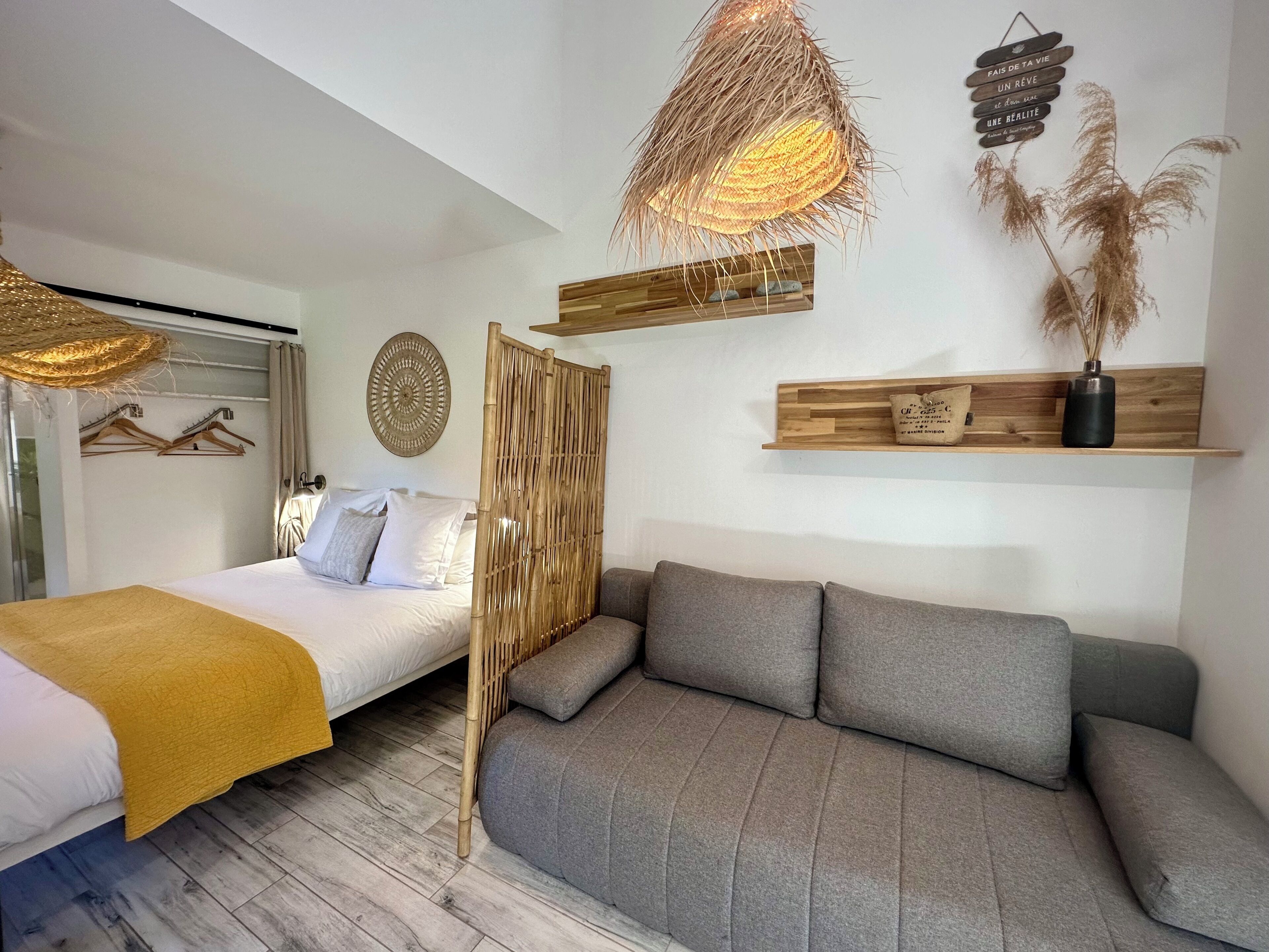 Un dormitorio con cama, sofá, un tapiz decorativo y una lámpara colgante.