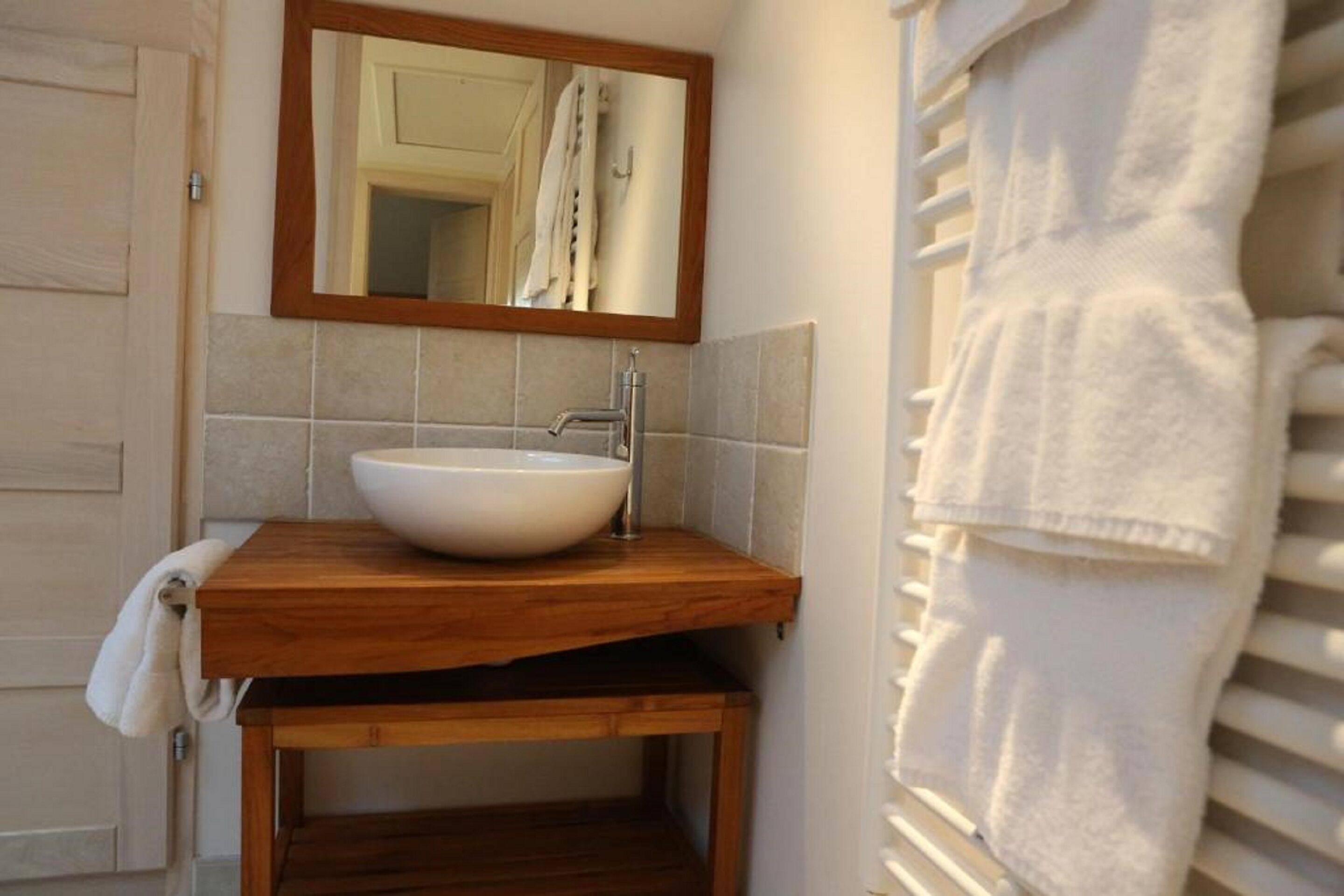 Une salle de bain avec un meuble-lavabo en bois, un lavabo blanc et un miroir au-dessus.