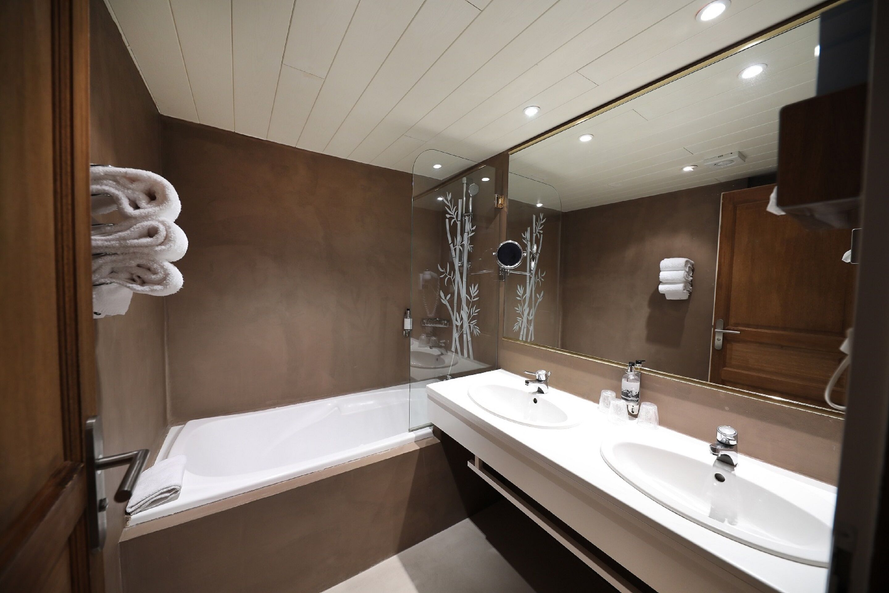 A modern bathroom with a bathtub, two sinks, and a large mirror.