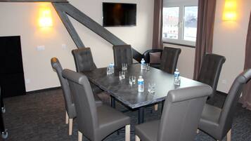A conference room with a dark table, six chairs, a flat-screen TV, and two wall-mounted lamps.