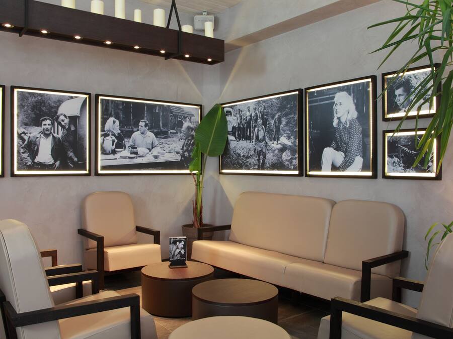 A modern lounge area with a sofa, chairs, and a coffee table. There are framed black and white photographs on the wall.