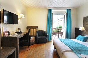 Een hotelkamer met een bed, bureau, stoel, televisie en een balkon met uitzicht.