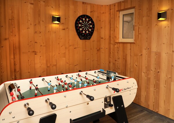 A foosball table in a room with wooden walls, a dartboard, and two wall-mounted lights. - Hôtel Restaurant de la Jamagne (Gerardmer)