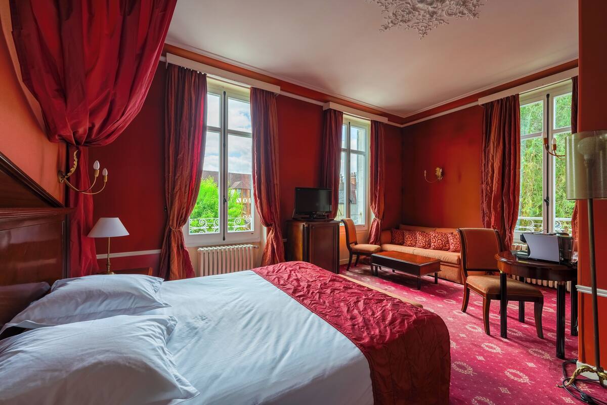 Een hotelkamer met een groot bed, een sofa, een bureau met een laptop en een televisie.