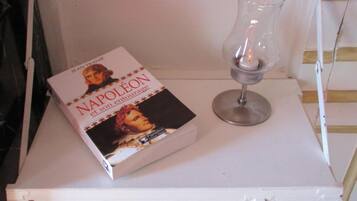 Un libro intitolato "NAPOLON" e un bicchiere trasparente su uno scaffale bianco.