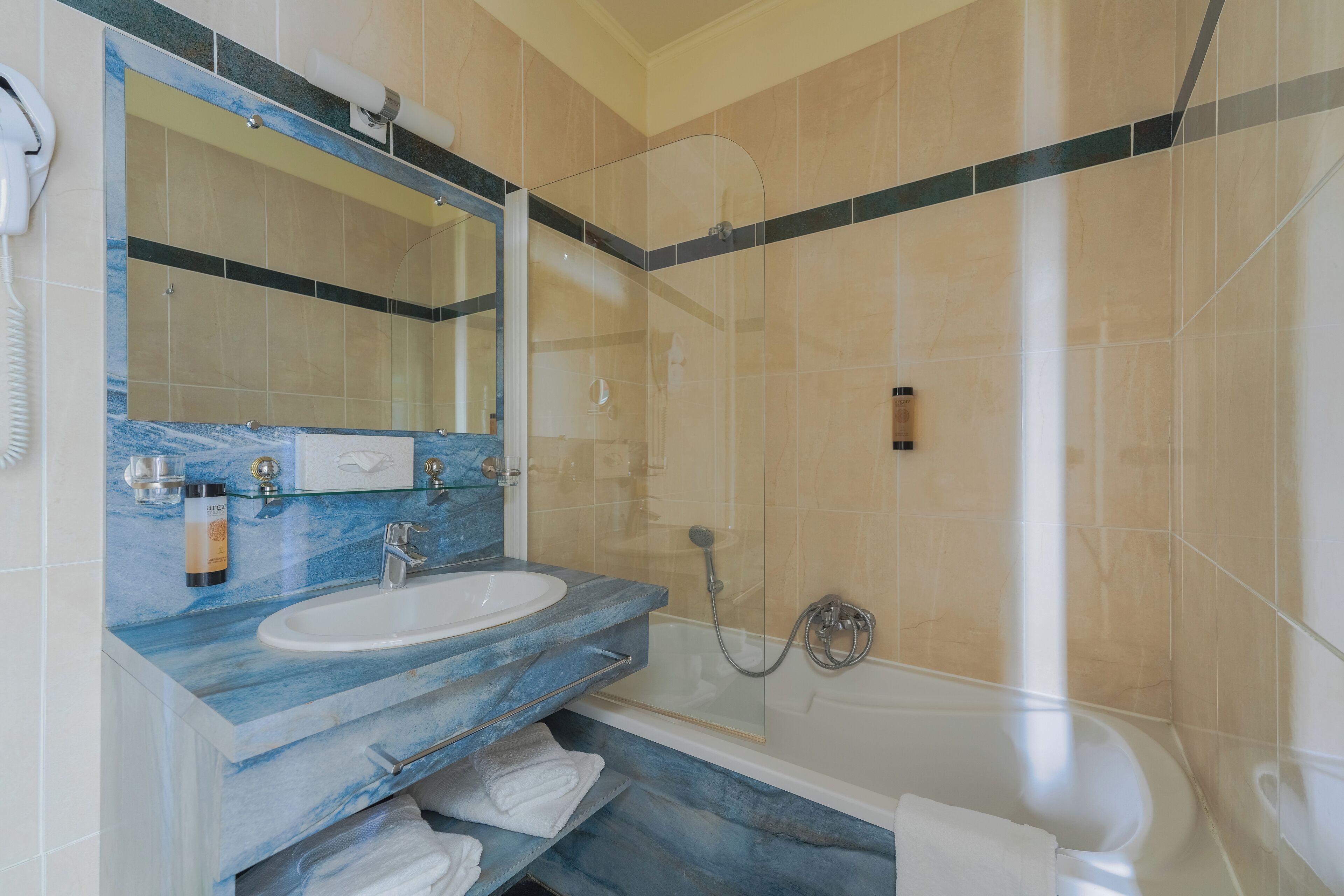 A bathroom with a marble sink, a glass-enclosed shower, and a white bathtub.