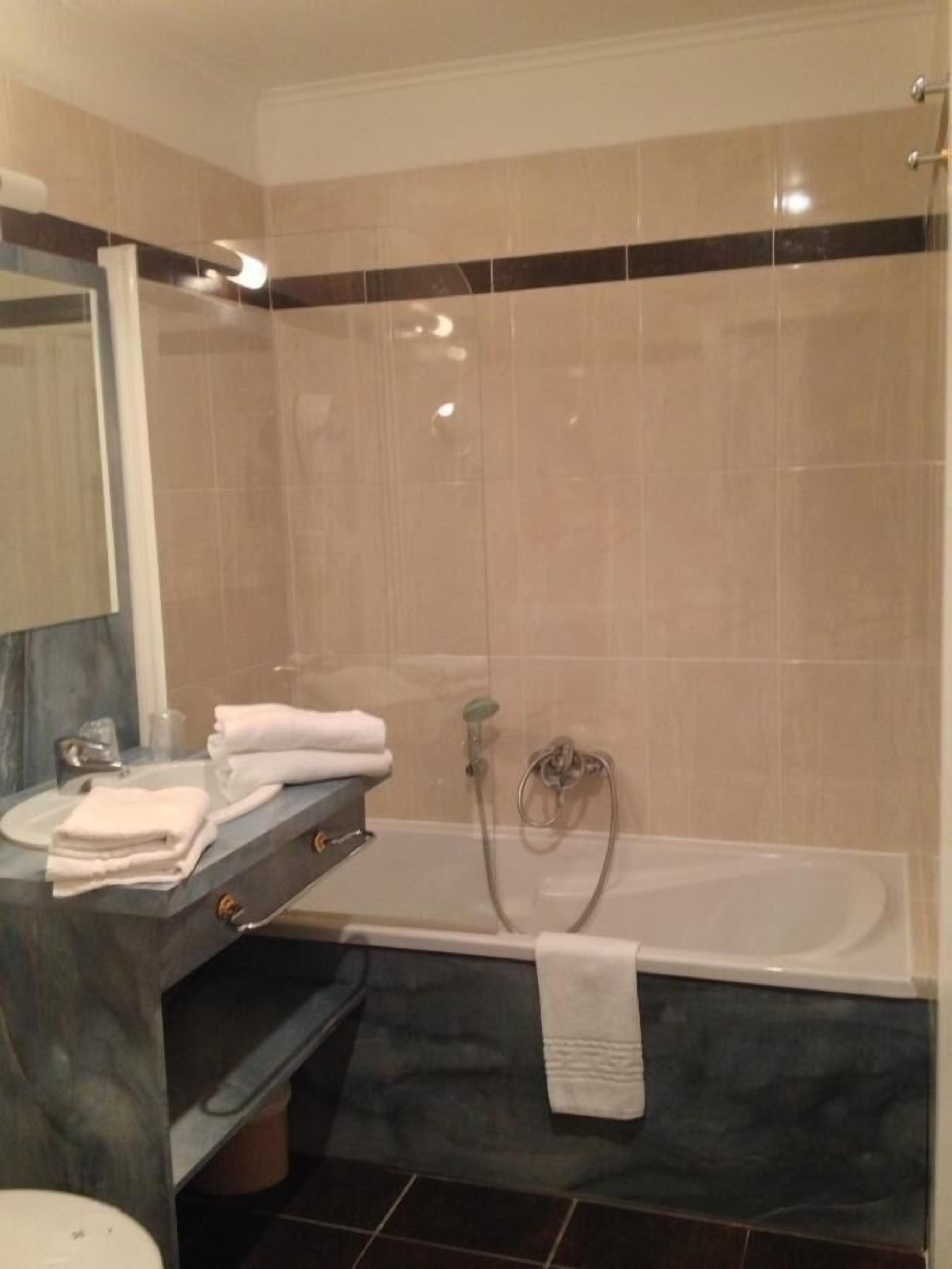 A modern bathroom with a bathtub, a sink with a marble countertop, and a mirror.