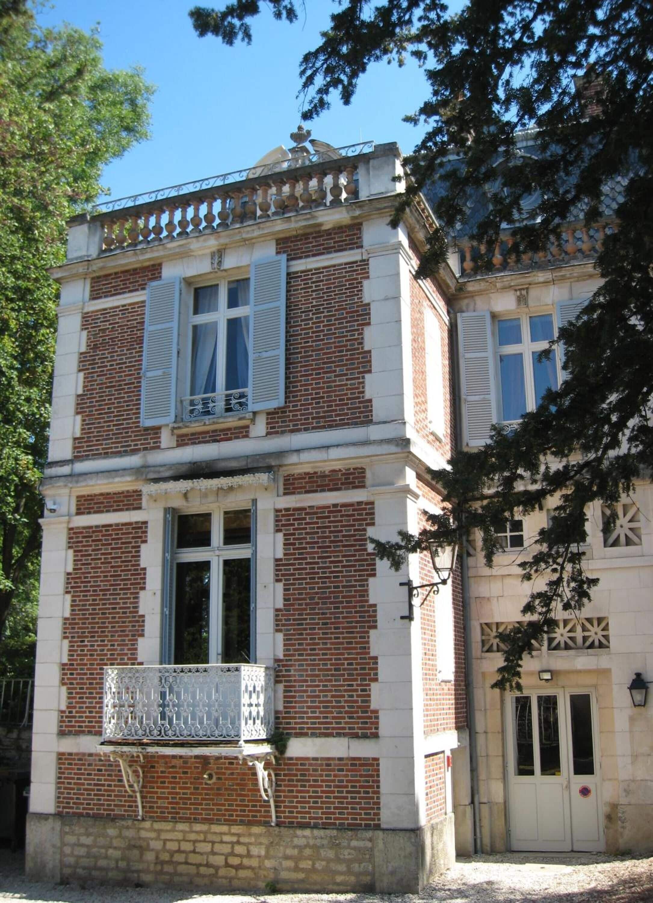 A two-story building with a brick facade and white window shutters.