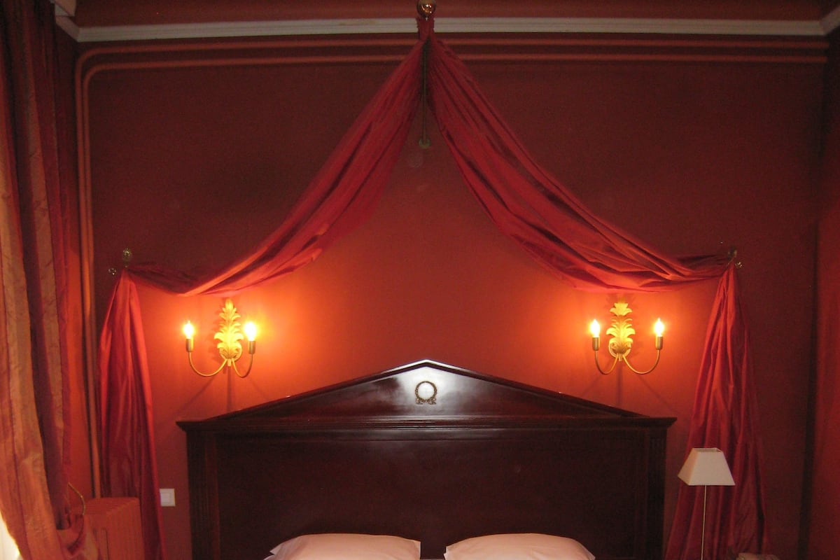 Een hotelkamer met een groot bed, een nachtkastje met een lamp en een telefoon.