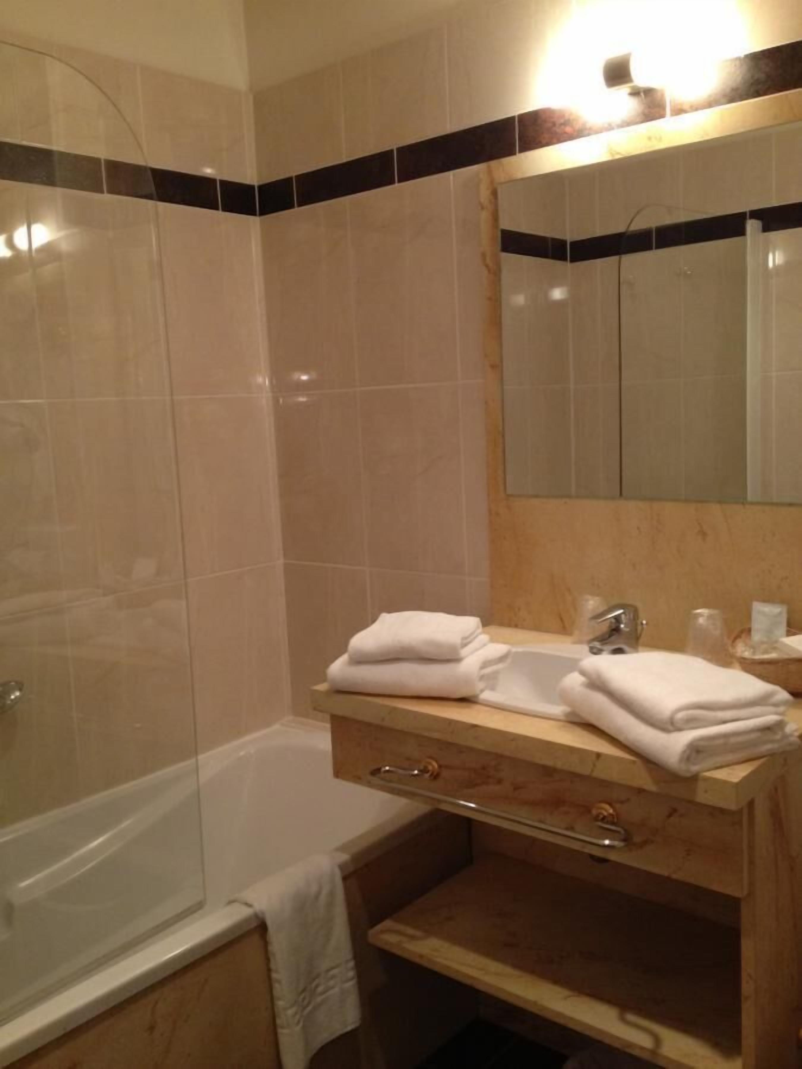 A bathroom with a glass shower enclosure, a wooden vanity with a mirror, and a bathtub.