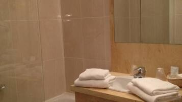 A bathroom with a glass shower enclosure, a wooden vanity with a mirror, and a bathtub.