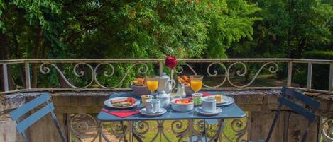 A table set with breakfast items, including toast, eggs, and fruit, on a balcony with metal railings and chairs.