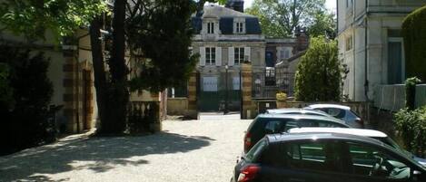 A street with parked cars and a building with a gated entrance.