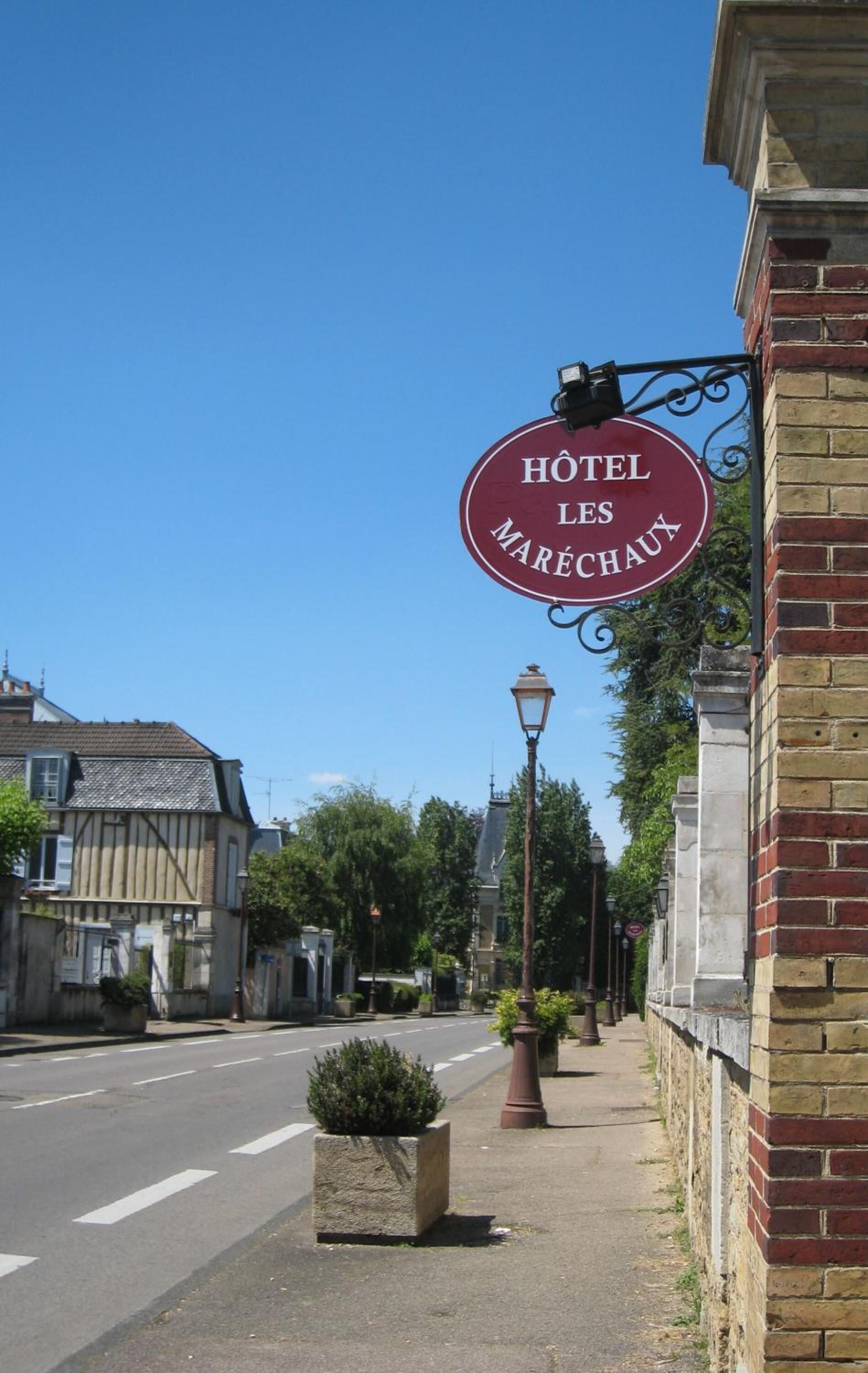 A street view with a sign for 'HOTEL LES MARÉCHAUX' hanging from a building.
