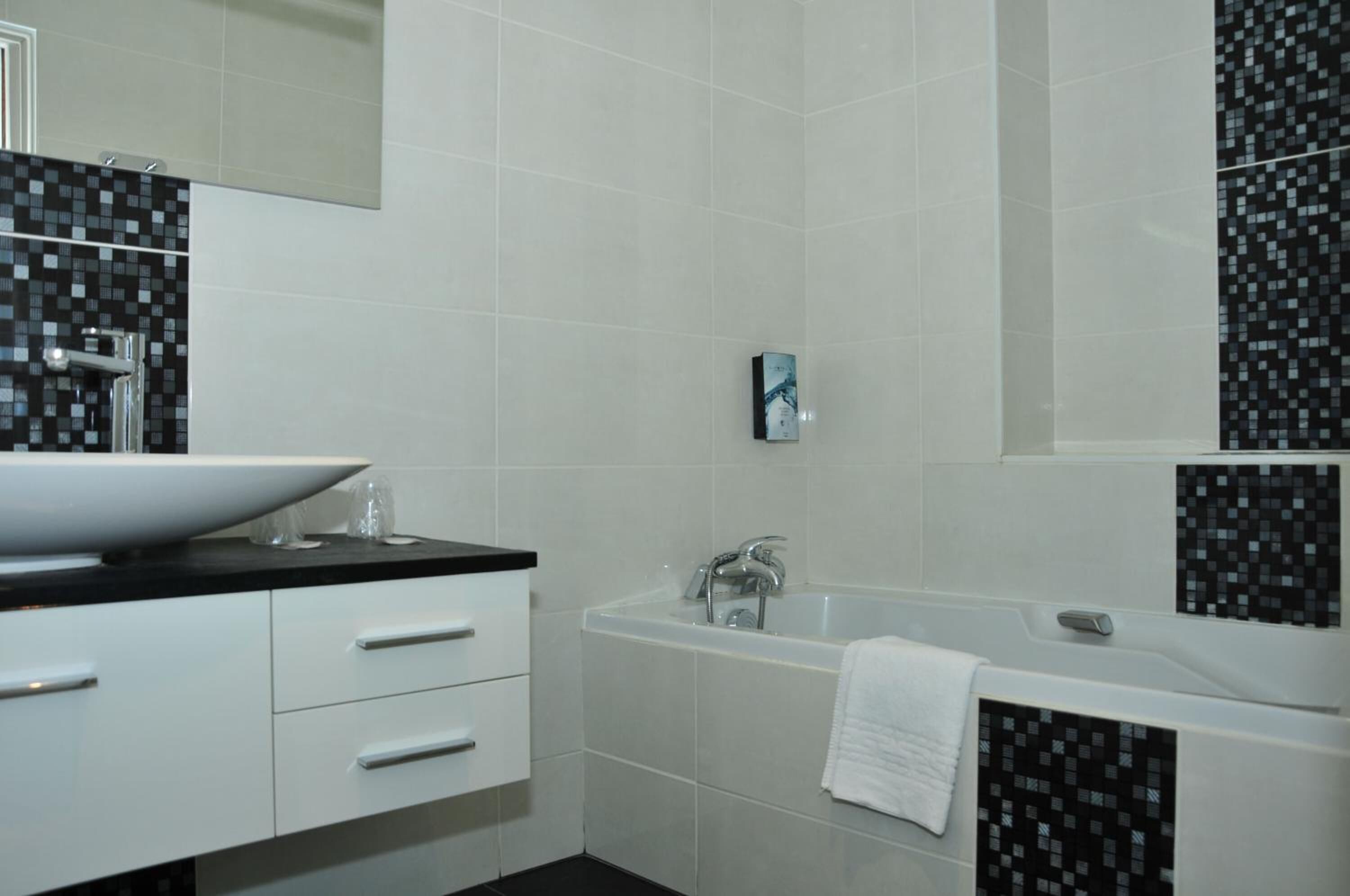 Ein modernes Badezimmer mit einem weißen Waschbecken, einer schwarzen Arbeitsplatte und einer großen Badewanne.