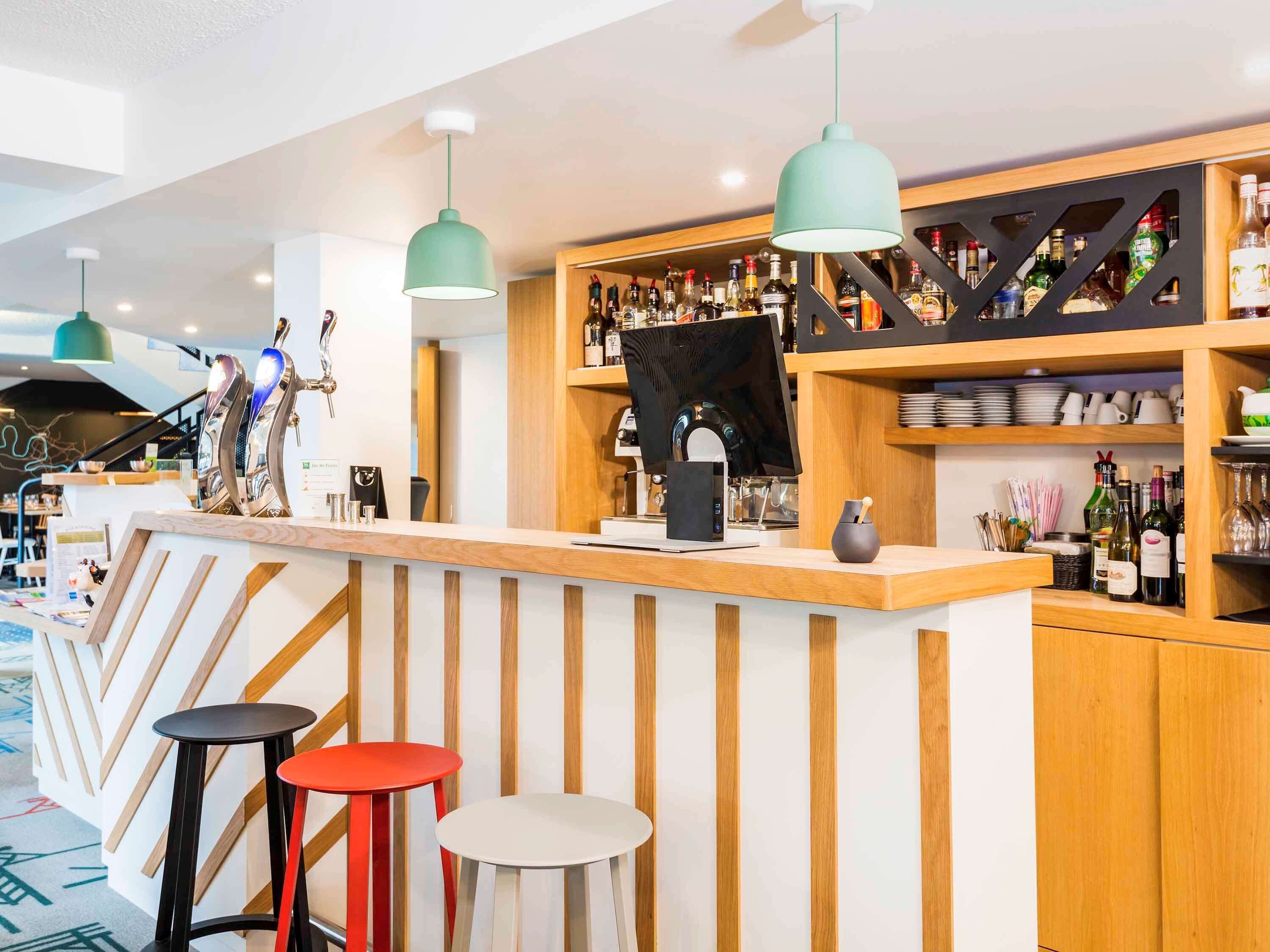 A bar area with a wooden counter, two stools, and hanging pendant lights.