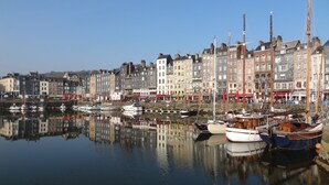 A harbor with boats docked, reflecting the buildings and sky.