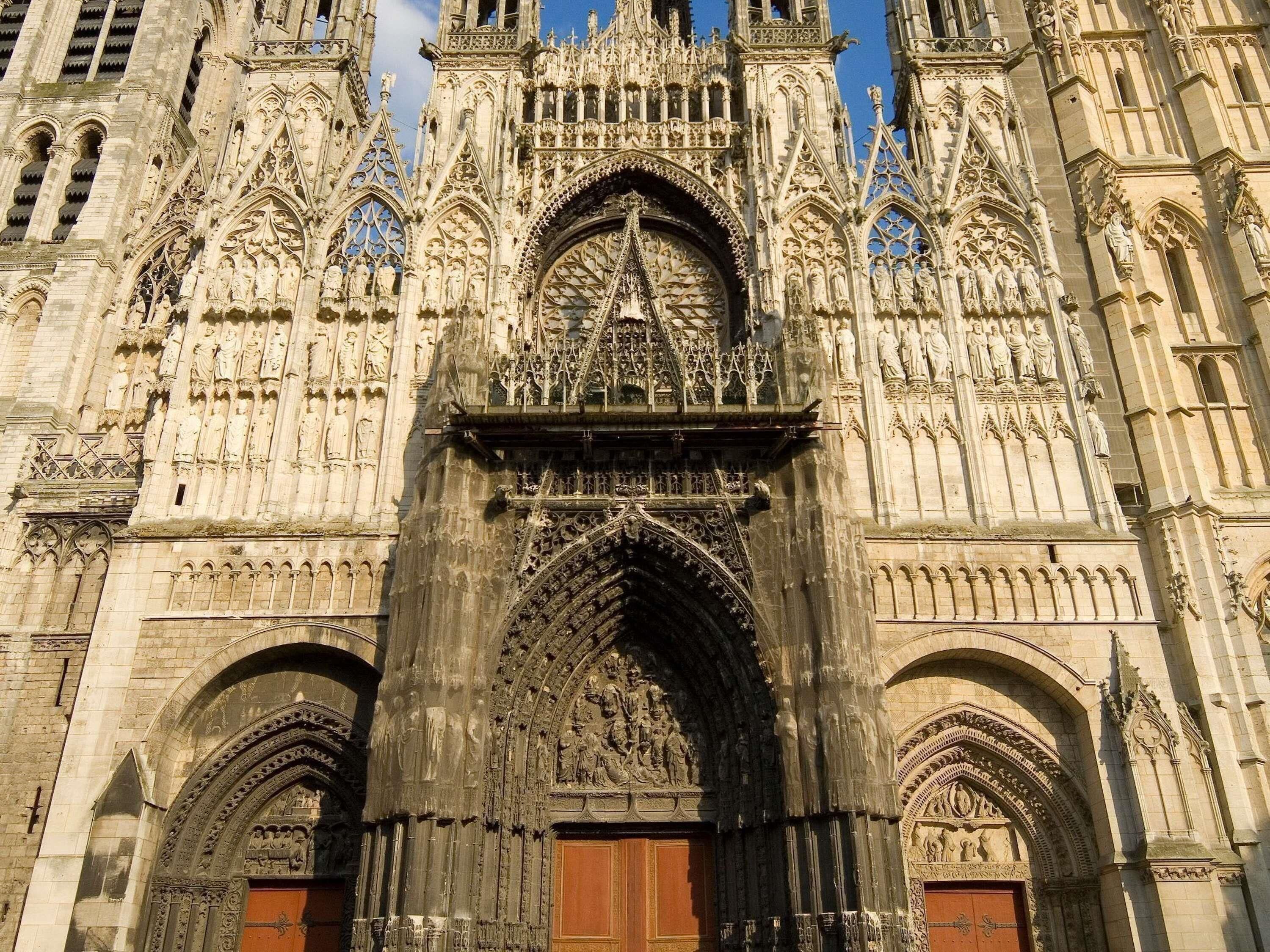 A Gothic cathedral with intricate stone carvings, a large central arch, and two smaller arches on either side.