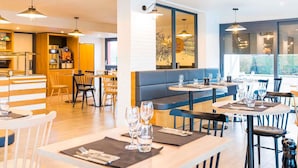 A modern restaurant with a bar area, seating, and large windows.