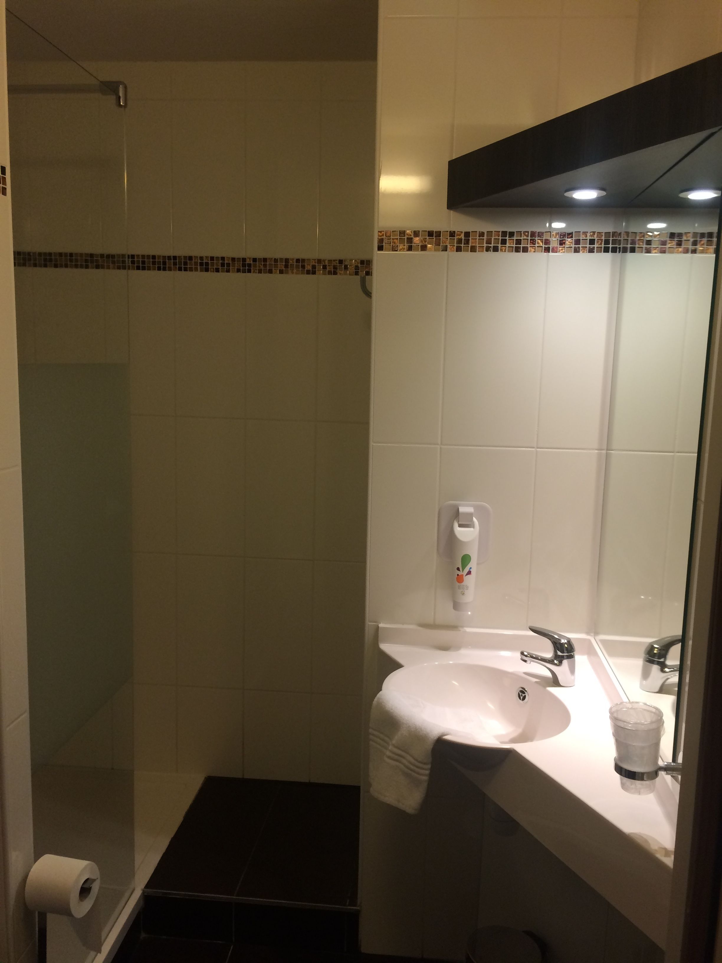 Un baño con ducha, lavabo, inodoro y secamanos.