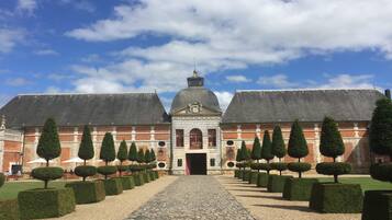 Een historisch gebouw met een symmetrische gevel, een centrale koepel en een geplaveid pad naar de ingang.