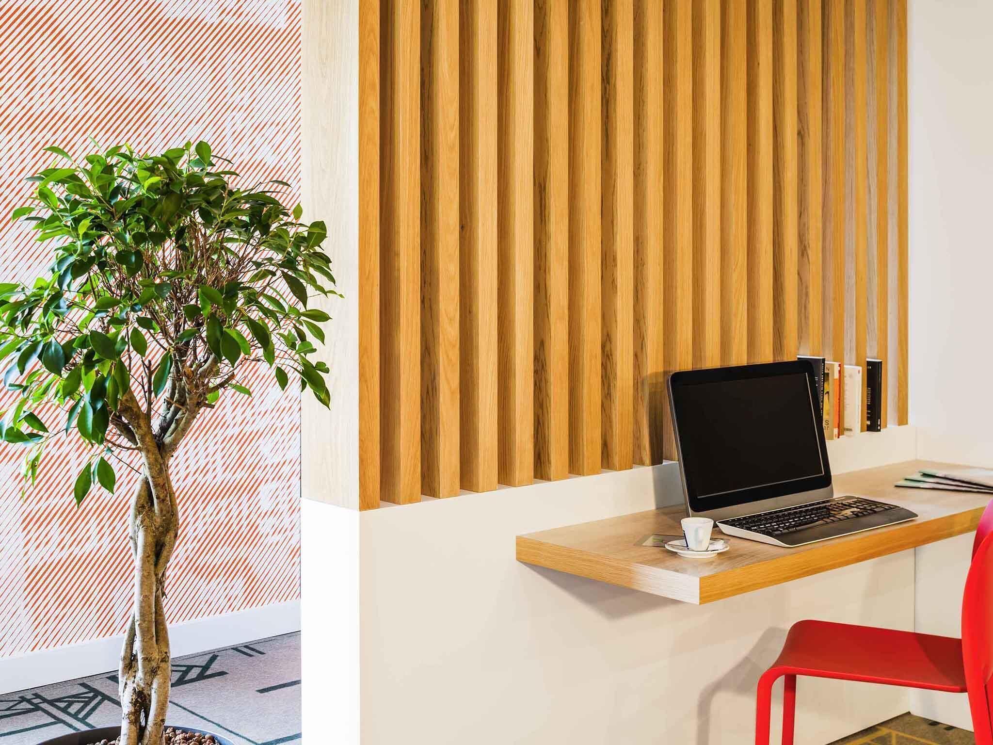 Un espacio de trabajo con una computadora portátil, una silla roja y una planta.
