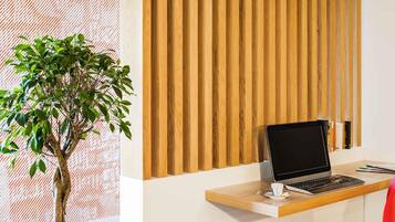 Un espacio de trabajo con una computadora portátil, una silla roja y una planta.